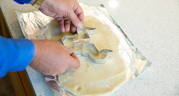 Dean Besterfield presses the cookie cutter into the dough to create the Bull U shape