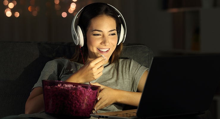 Female student watching a movie at home and eating popcorn finding a way to have summer break fun by social distancing.