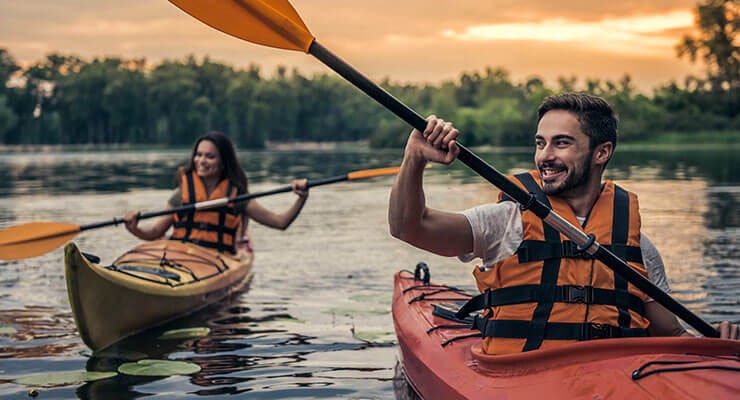 Couple having summer break fun by social distancing and going kayaking..