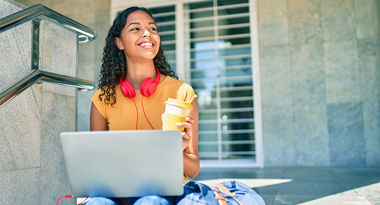 Student studying outside with her laptop and earphones