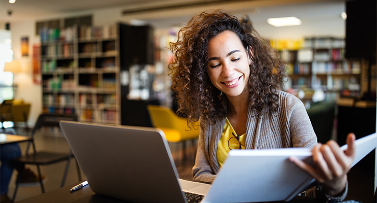 female high school student in a library studying for the PSAT / NMSQT test to become a national merit scholar.