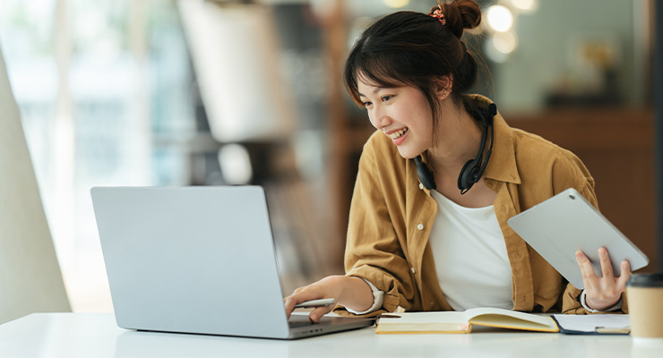 A sophomore student using a laptop and a tablet.