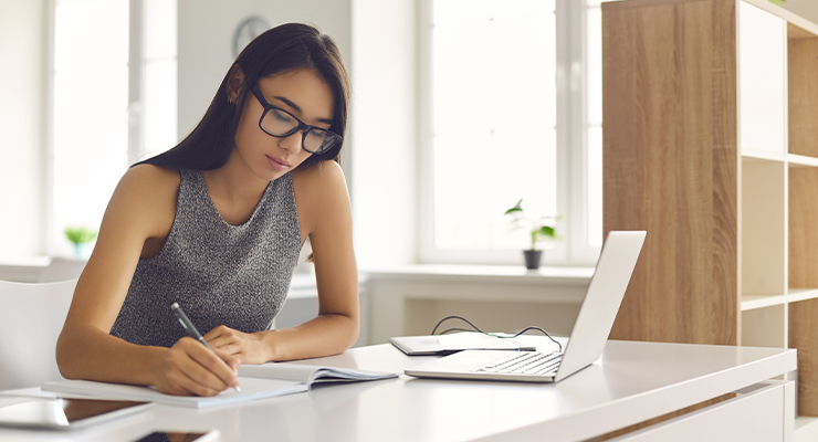 High school student sitting at a desk taking notes about honors college program offers.