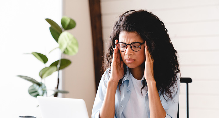 A female holding her head while researching factors to ignore when picking a college.