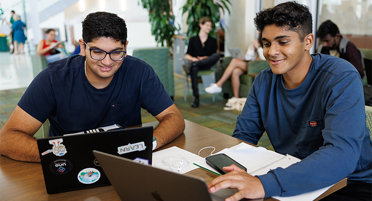 Two USF students using their laptops to study.