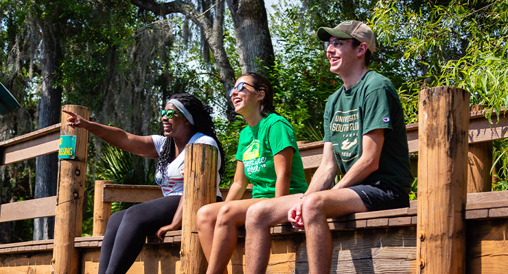 Three USF students sitting outside on a dock.