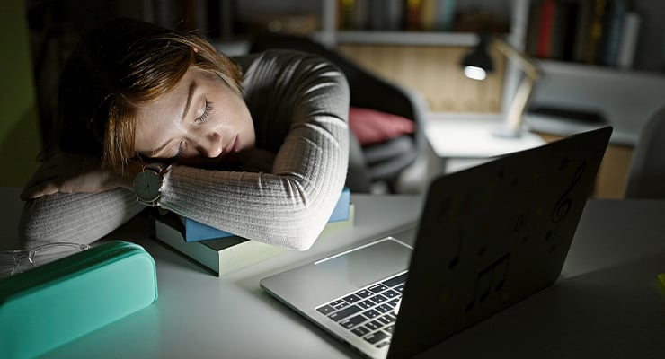 A student sleeping while studying on a desk.