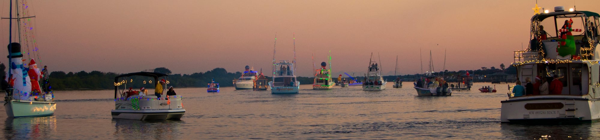 A bunch of boats on the water decorated for Christmas.