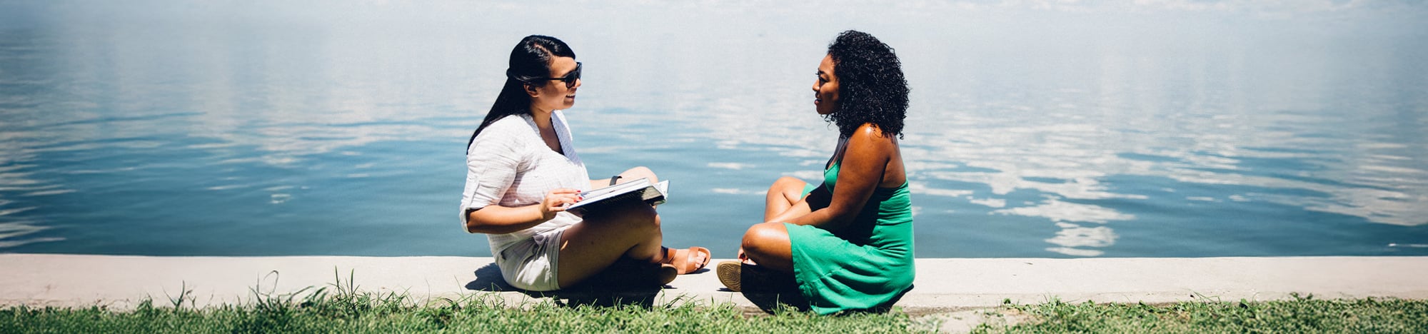 Two college students sitting together by the water.