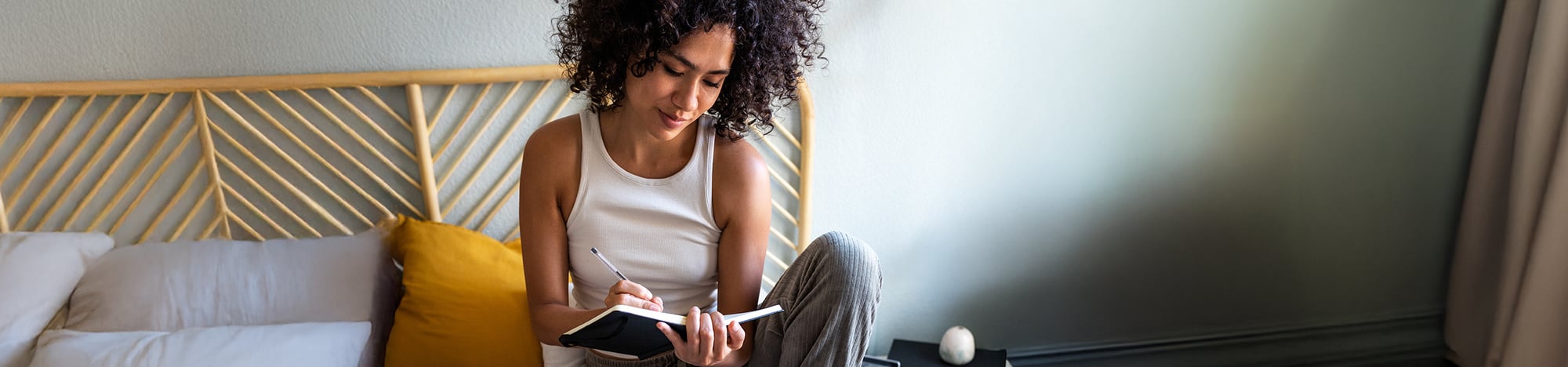 A college student journaling in bed.