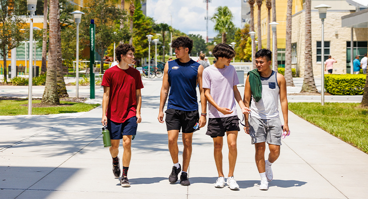 Four students walking on campus together.