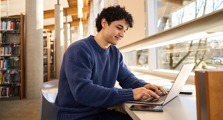 A student using his laptop in a library.