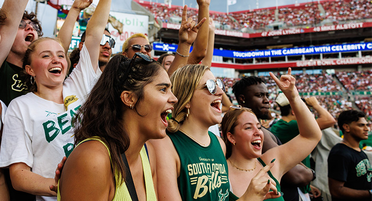 Multiple students cheering in the student section at a USF football game.