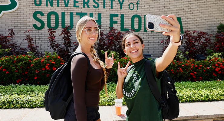 Two USF students taking a selfie and holding up the Bulls symbol.