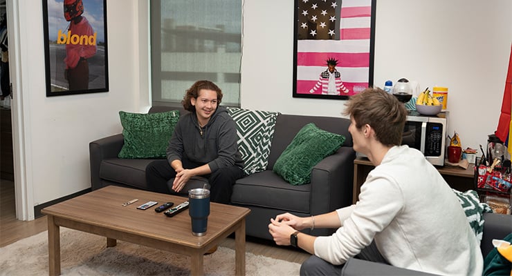 Two male students hanging out in the living room of their off-campus apartment.