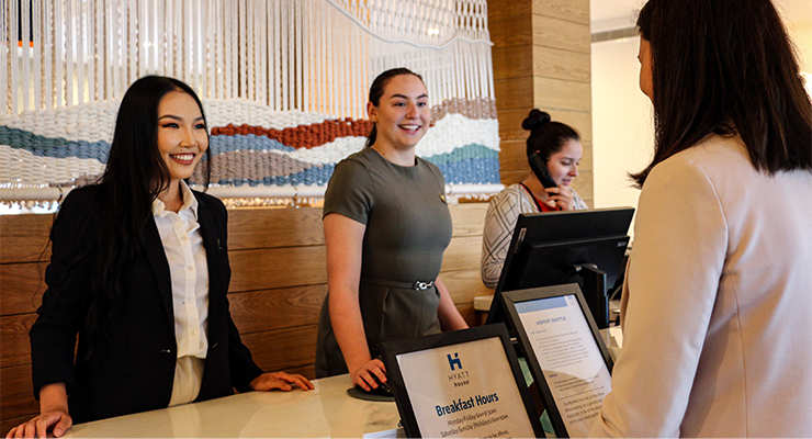 Two women standing behind a hotel reception desk. 