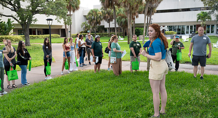 Campus tour guide surrounded by prospective students and their family.
