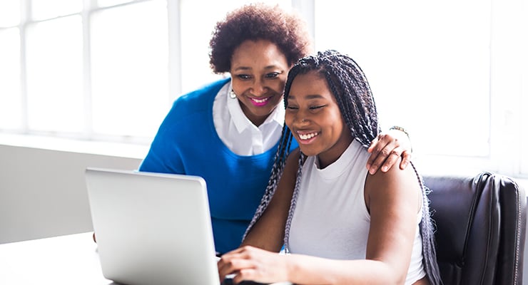 A counselor offering guidance and support to a student working on a laptop.