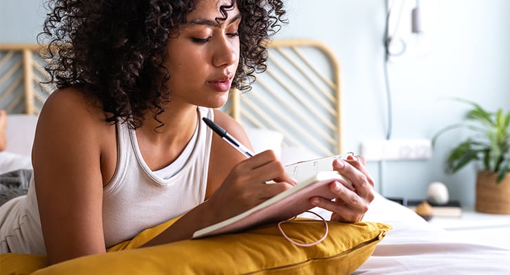 A girl taking notes on bed.