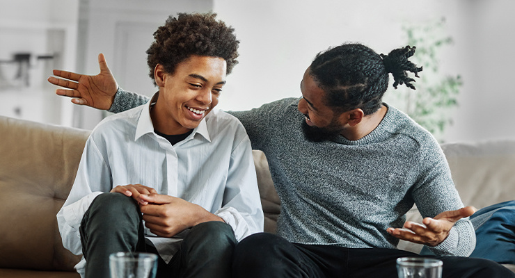Two smiling men sitting on a couch.