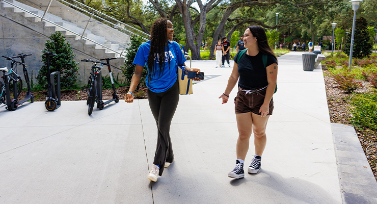 Two USF students talking and walking to class together.