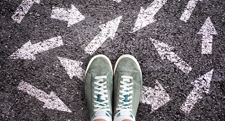 A person standing on a road with arrows pointing in different directions.