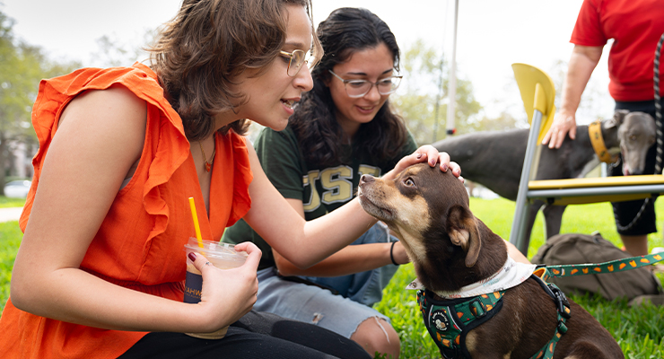 Two young women spending time with a therapy dog during Paws and Relax.