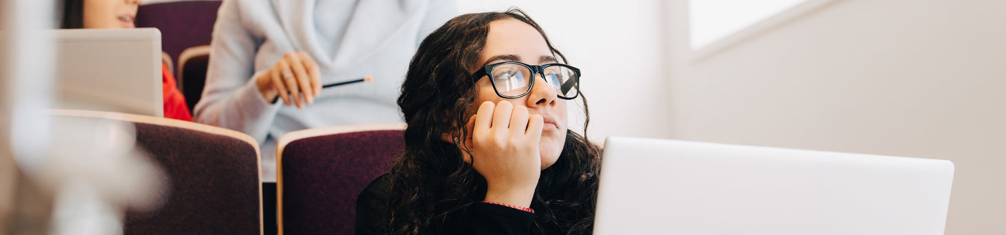 Female student wearing glasses sitting in class.