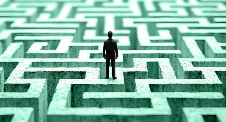 A man standing on top of a green maze, contemplating his next move.