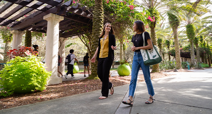 A college counselor walking around campus talking to one of her students.