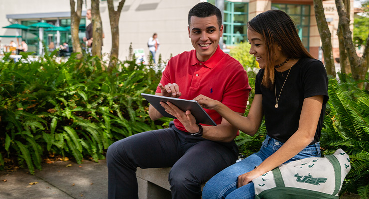 A college counselor helping a student by the bookstore on campus.