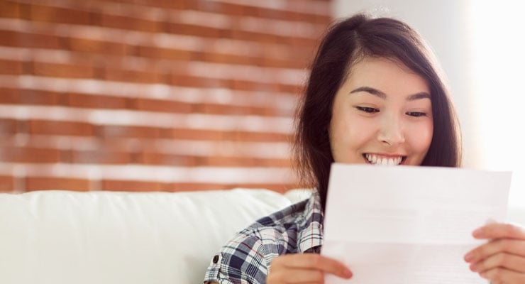 A high school student reads an accepted to college decision letter.