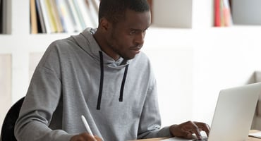 African-American student sitting in front of his laptop preparing for the ACT test.