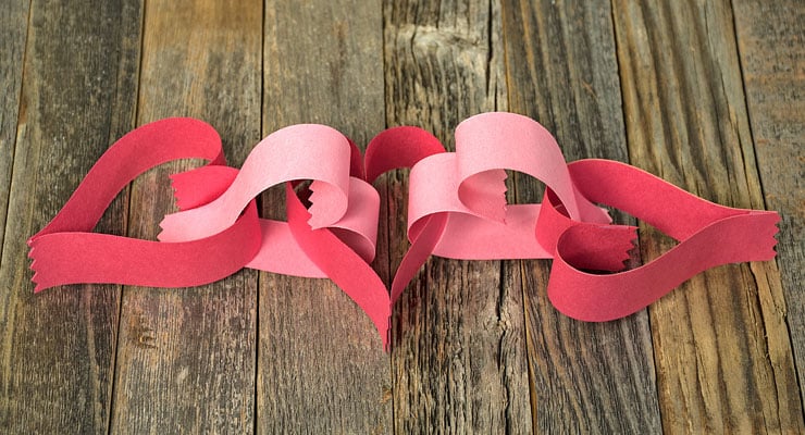 Pink and red heart-shaped paper garland on a wood-plank floor