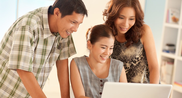 A father and a mother help their daughter with a college application.