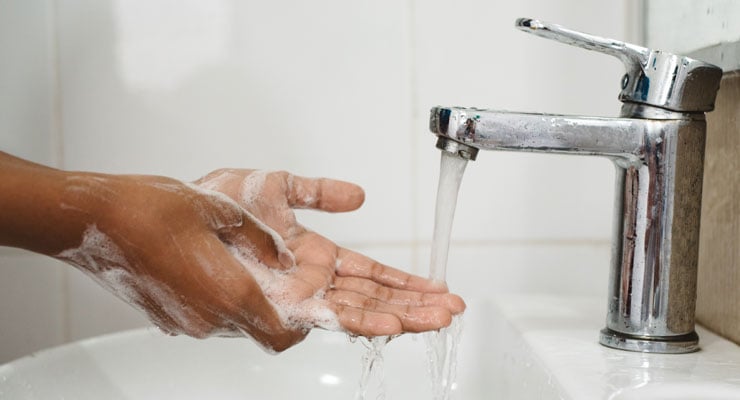 A woman washes her hands under running water