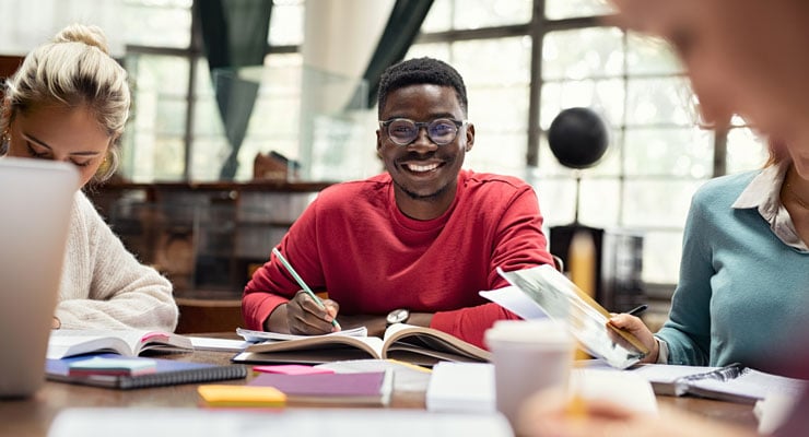 A group of students sit at a table with their books for a study session.