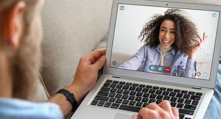 A male student interacts with his online class instructor on a laptop