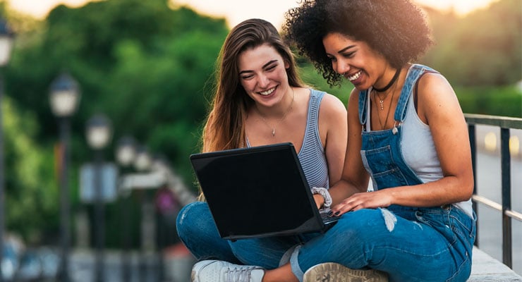 Two first-generation college students work on a computer together.