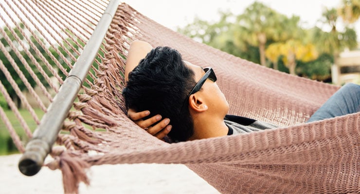 USF student relaxing in a hammock at Castor Beach on campus.