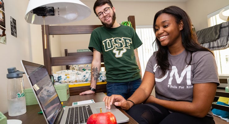 Two USF students studying life skills they need for college in their dorm room.