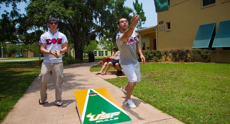 USF fraternity brothers playing corn hole outside of their frat house