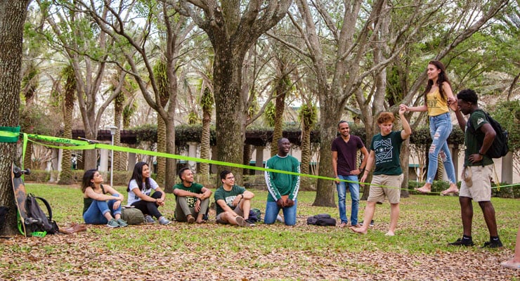 USF students walking on a ropes course and helping each other finish the course.