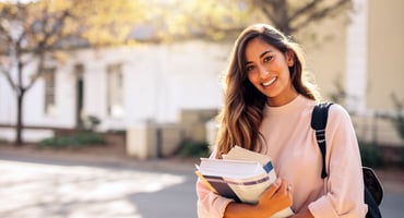 A student stands on campus with her books