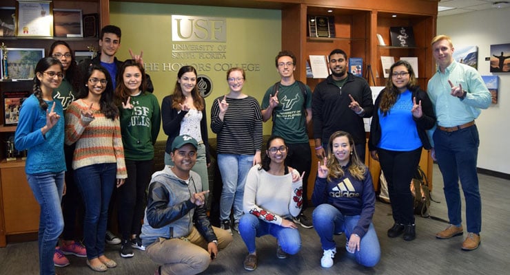 USF Honors College students standing next to the Honors College sign.