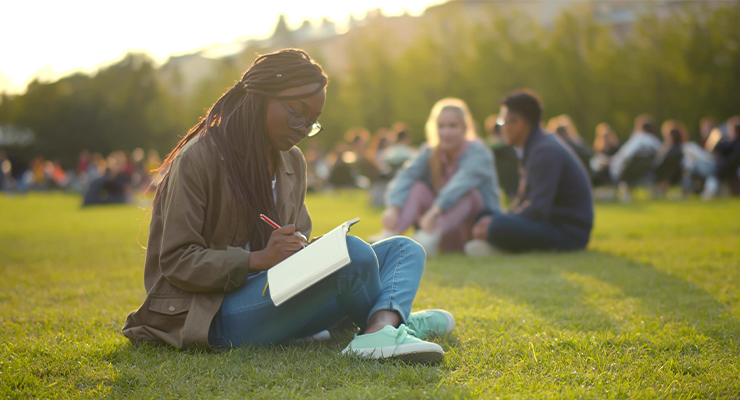 Student practicing a healthy habit by studying outside in nature during her first college semester.