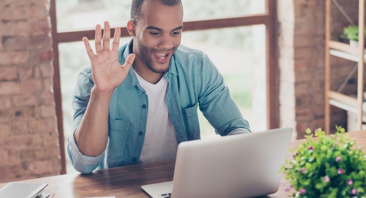 male student raising his hand at home on his laptop in his online class.