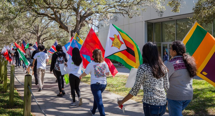 USF students march through the campus holding their country's flag during a multicultural event.