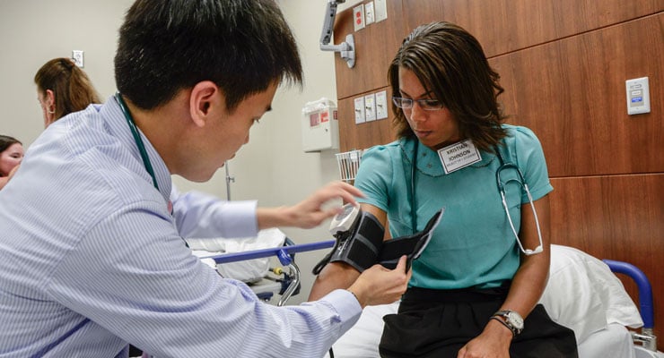 USF students in a medical type major take a person's blood pressure.