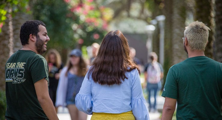 Three USF students take a walk at the MLK Plaza on campus.